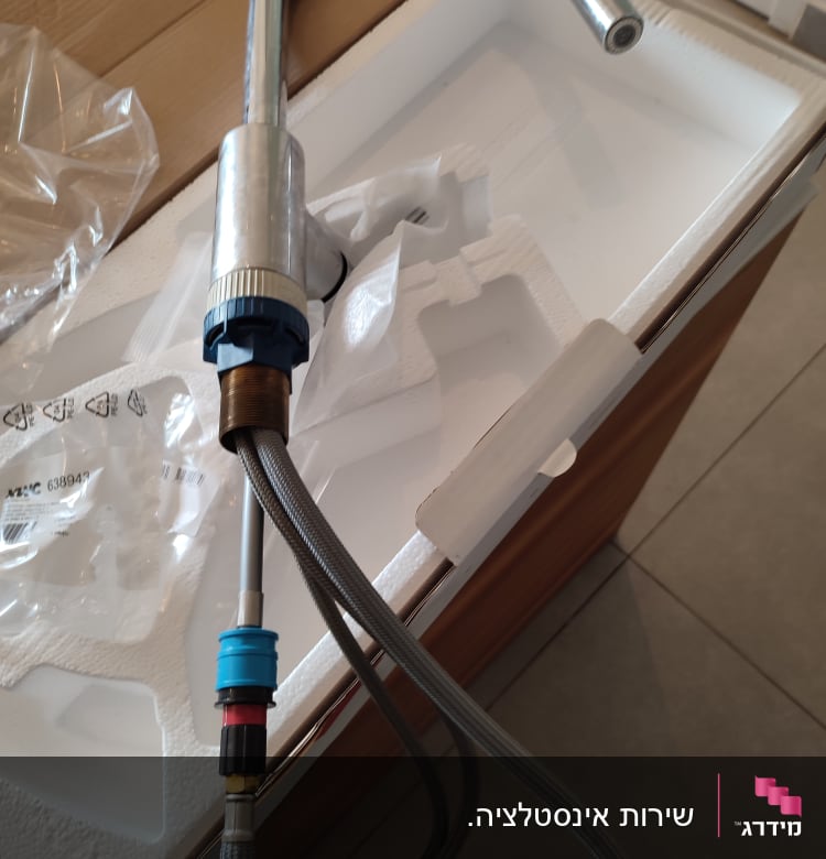 ברז מטבח עם צינורות חיבור על קרטון